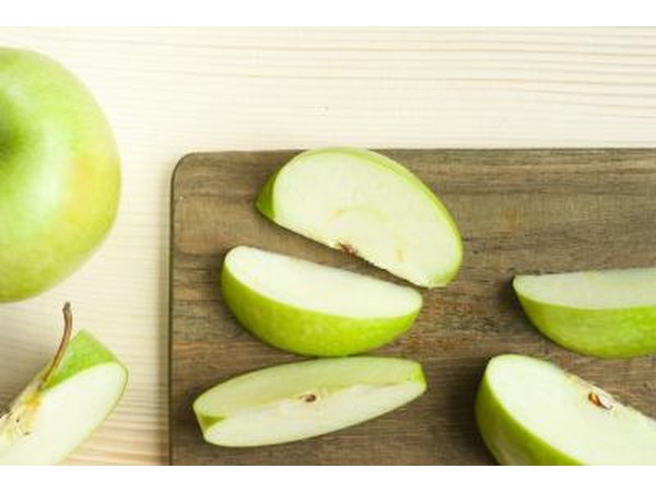 Green apple slices on a wooden cutting board.