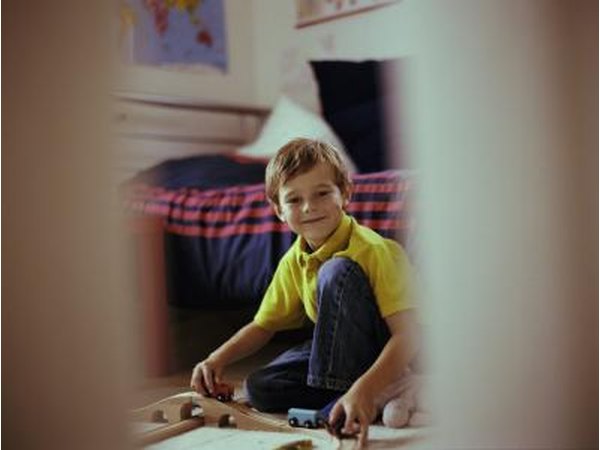 Open door with smiling young boy playing in bedroom.