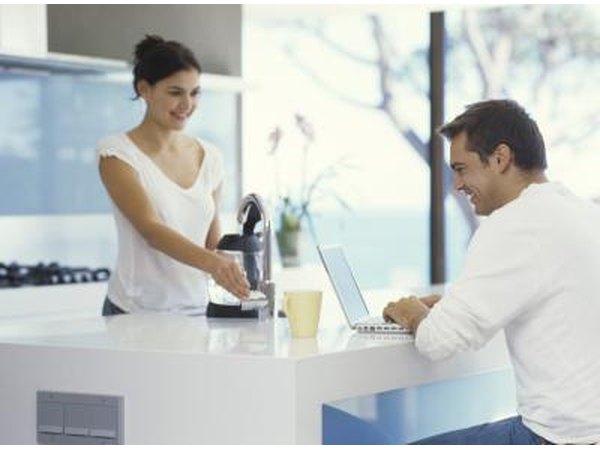 A woman and man are sitting in a simple, modern kitchen.