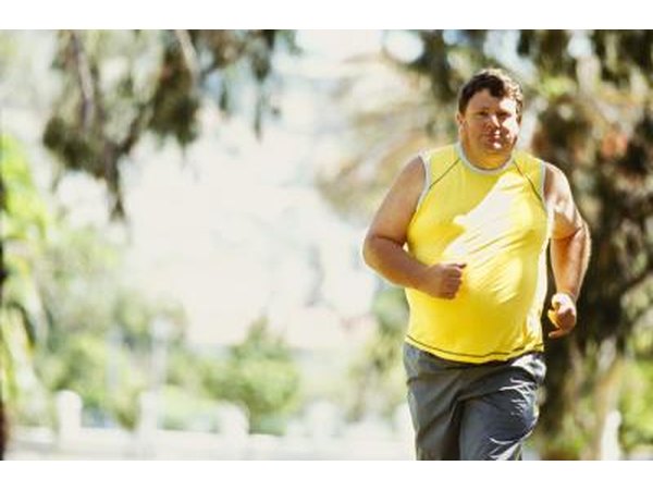 An overweight man runs in the park.