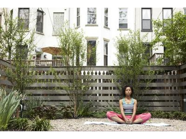 A young woman sits in bound angle pose on an urban patio.
