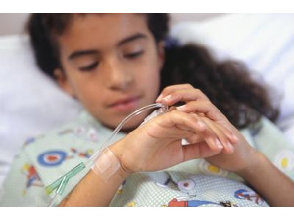 A girl looks at her IV in a hospital bed.