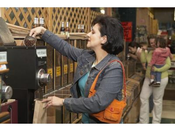 Woman pouring coffee beans into grinder at supermarket