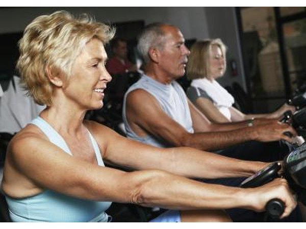 Mature people on stationary bikes at the gym.