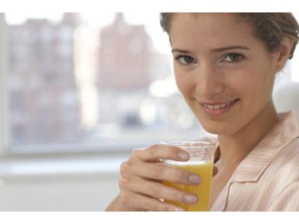 Woman holding glass of orange juice.