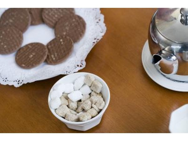 Light brown evaporated cane juice cubes and refined white sugar cubes in a bowl.