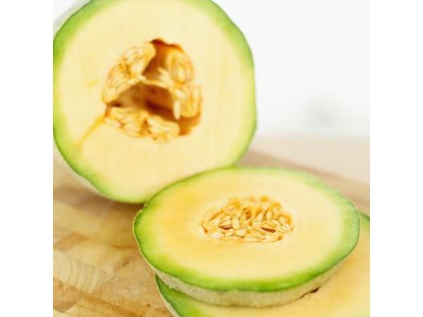 A cantaloupe sliced on a cutting board.