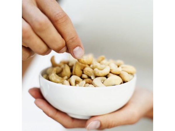 A man eats cashews from a bowl.