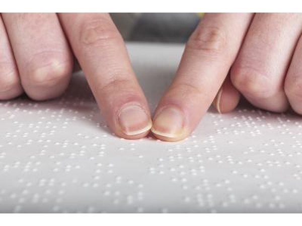 Fingers reading Braille book.