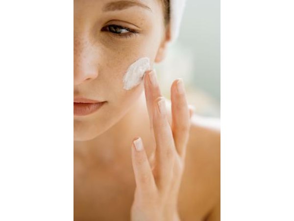 Woman putting cream on her face