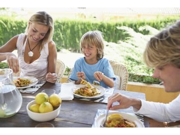 Boy eating at table with parents outdoors