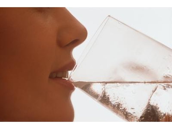 A woman drinks a glass of water.