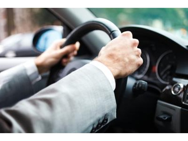 Close up of hands on a steering wheel.