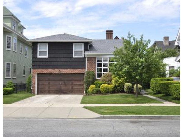 A sidewalk lined with hedges cutting through the yard of a suburban home.