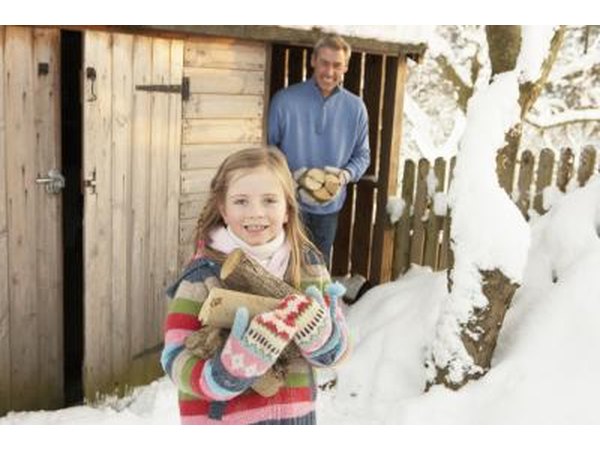 A father and daughter step outside of a firewood shed.