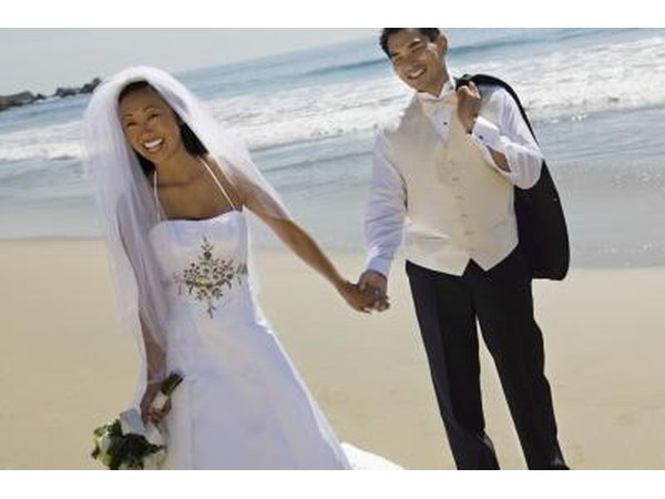 Bride and groom holding hands on beach