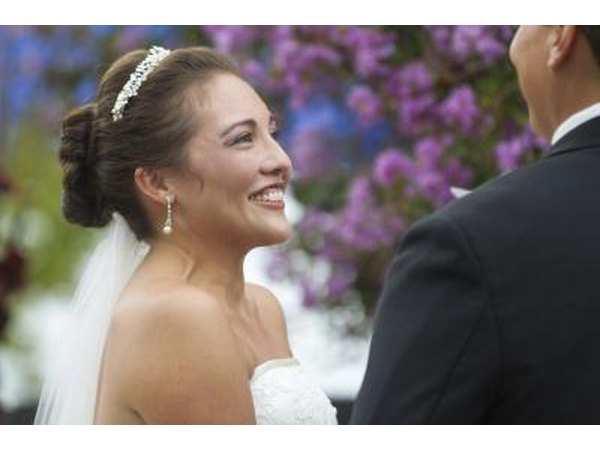 The bride smiles while listening to the groom during a wedding ceremony.