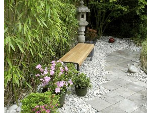 A sidewalk lined with a bench, japanese lantern and pots of flowers.
