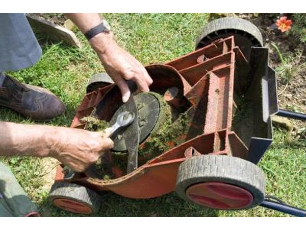 Close-up of a man cleaning lawn mower blades