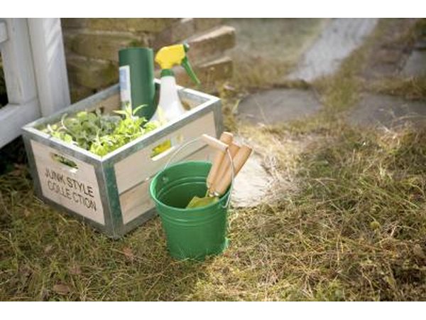 Gardening supplies in a wooden crate outdoors.