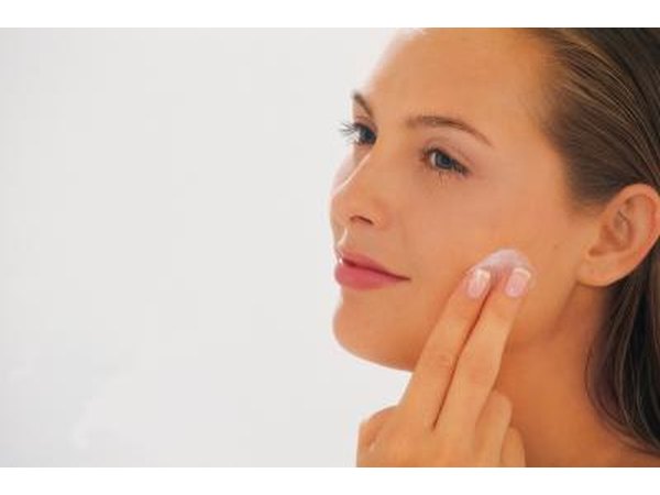 woman applying cream to face