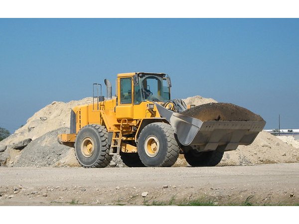 A front loader hauls dirt on a construction site.