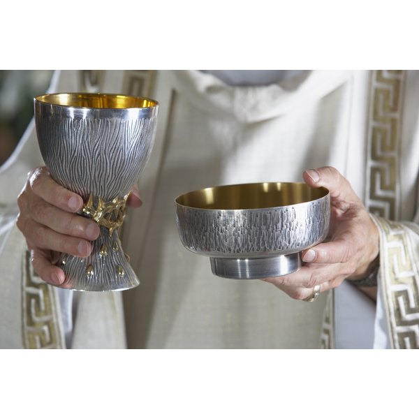 Brand X Pictures/Brand X Pictures/Getty Images Priest holding goblet and communion bowl