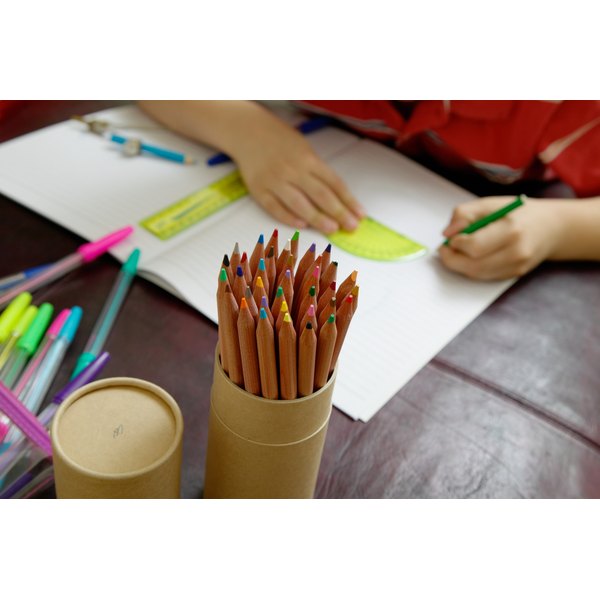 Ableimages/Photodisc/Getty Images Boy (6-8) using protractor, focus on pot of pencils, close up