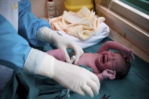 Neonatologist with newborn on table
