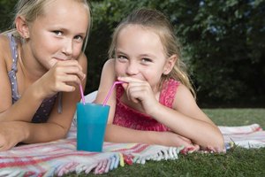 Two girls drinking from a cup with straws.