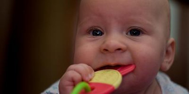 baby bites a teething toy, close-up image by Alexander Gorelik from Fotolia.com Teething usually begins at around 6 months of age.