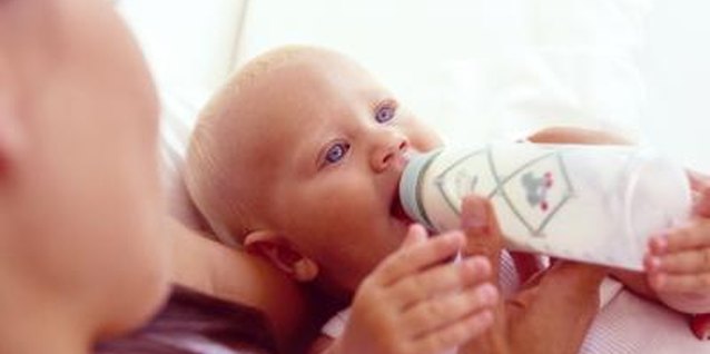 Pixland/Pixland/Getty Images Hold the baby so that his head is propped up slightly while feeding him a bottle.