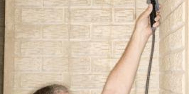 Jupiterimages/liquidlibrary/Getty Images Spray a coat of acid-etch concrete stain to make split face concrete wall resemble natural stone.