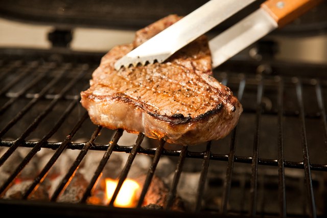 Moving steak on grill with tongs.