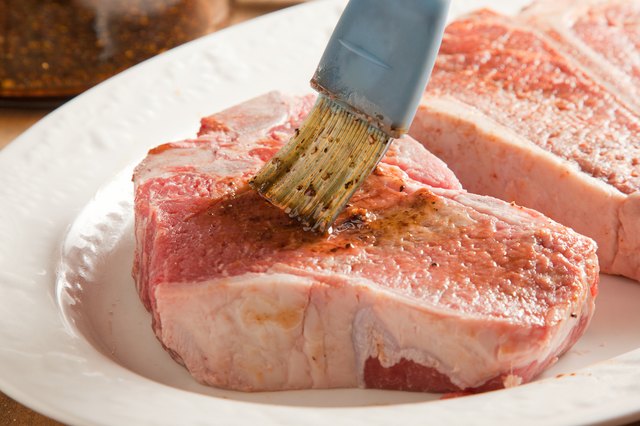 Raw t-bone steaks brushed with marinade.