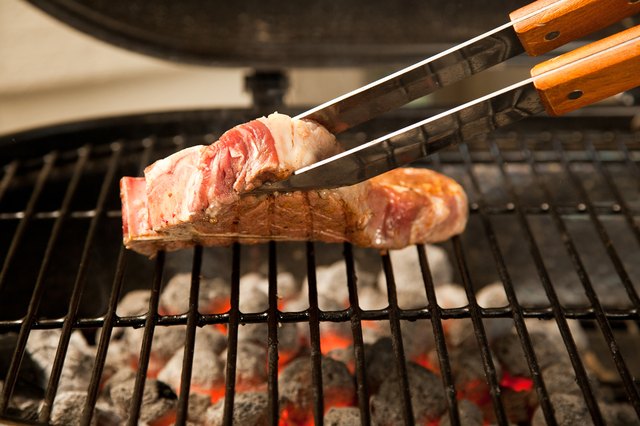 Flipping steak on grill with tongs.