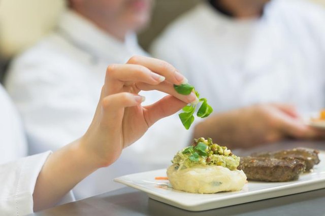 A chef putting a garnish on mashed potatoes.