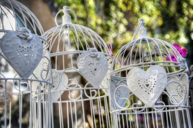 White bird cages on an outdoor table.