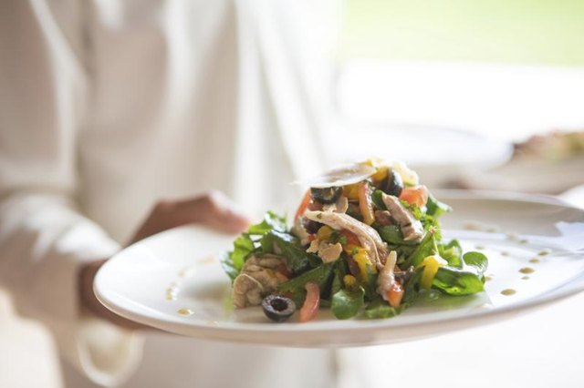 A waiter brings out a salad entree.