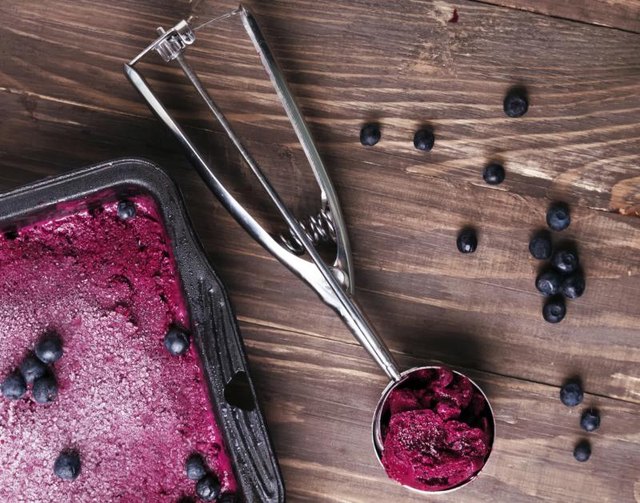 Berry sorbet in a pan, next to a spoonful of sorbet