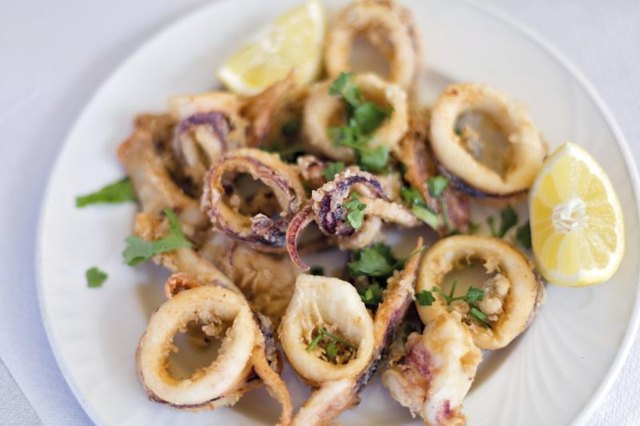 A plate of calamari with a lemon wedge.