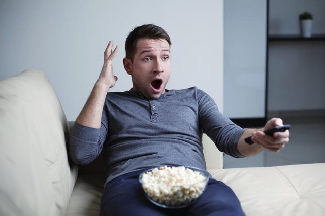 Surpised man watching a movie with popcorn.