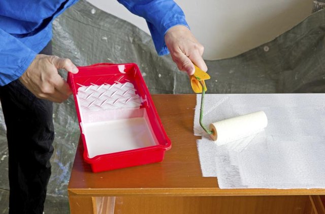 A man priming a wooden cabinet. A man priming a wooden cabinet.