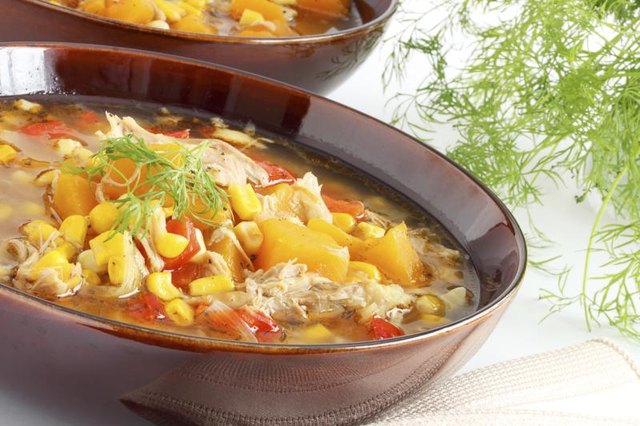 A bowl of chicken and corn in a broth.