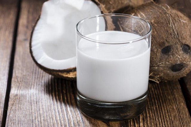 A borken coconut and glass of coconut milk.