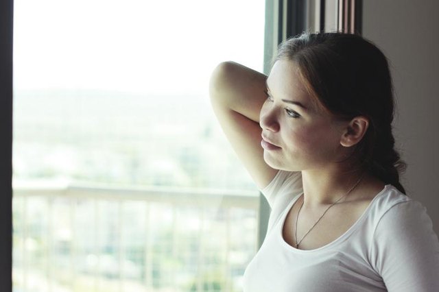 A contemplative woman thinking while looking out of a window.