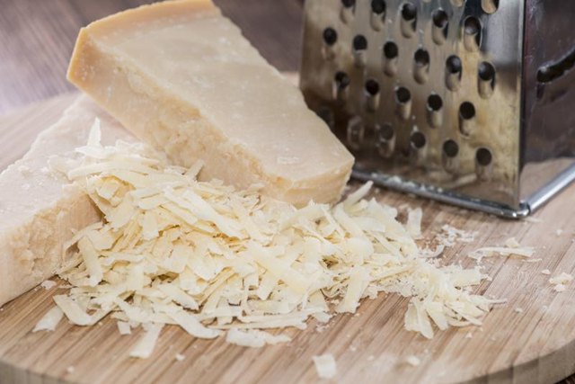 Grated Parmigiano-Reggiano cheese on cutting board.