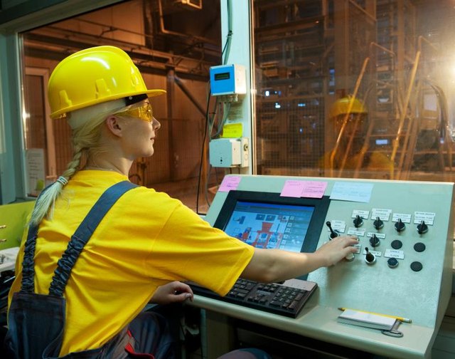 A female factory worker controlling equipment.