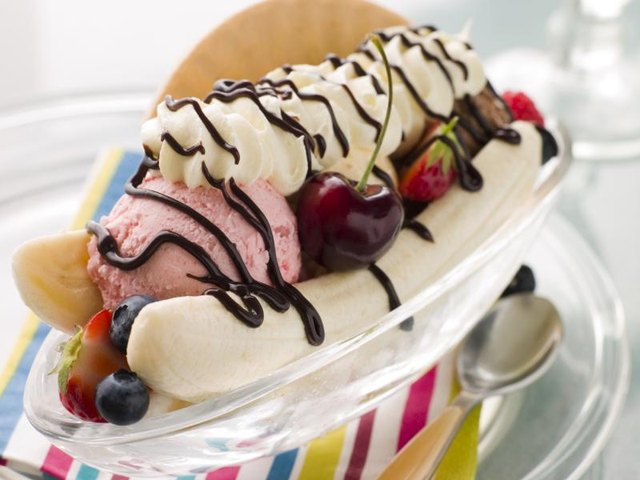 A banana split with icecream, fresh fruit and chocolate syrup.