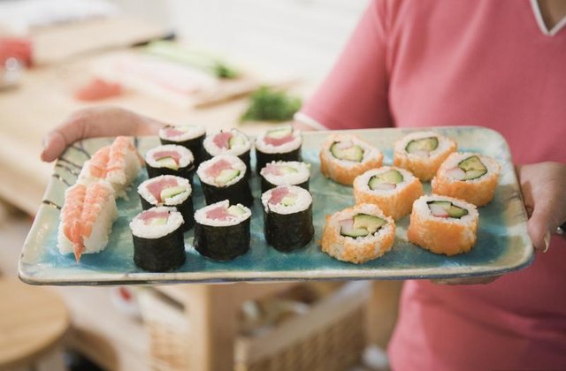 Woman holding up sushi tray.